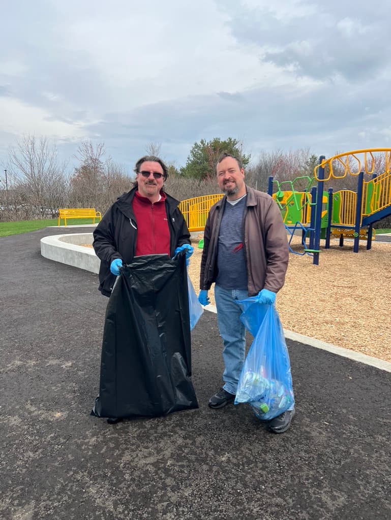Doug Maskell and a volunteer holding cleanup bags near a Caledon playground