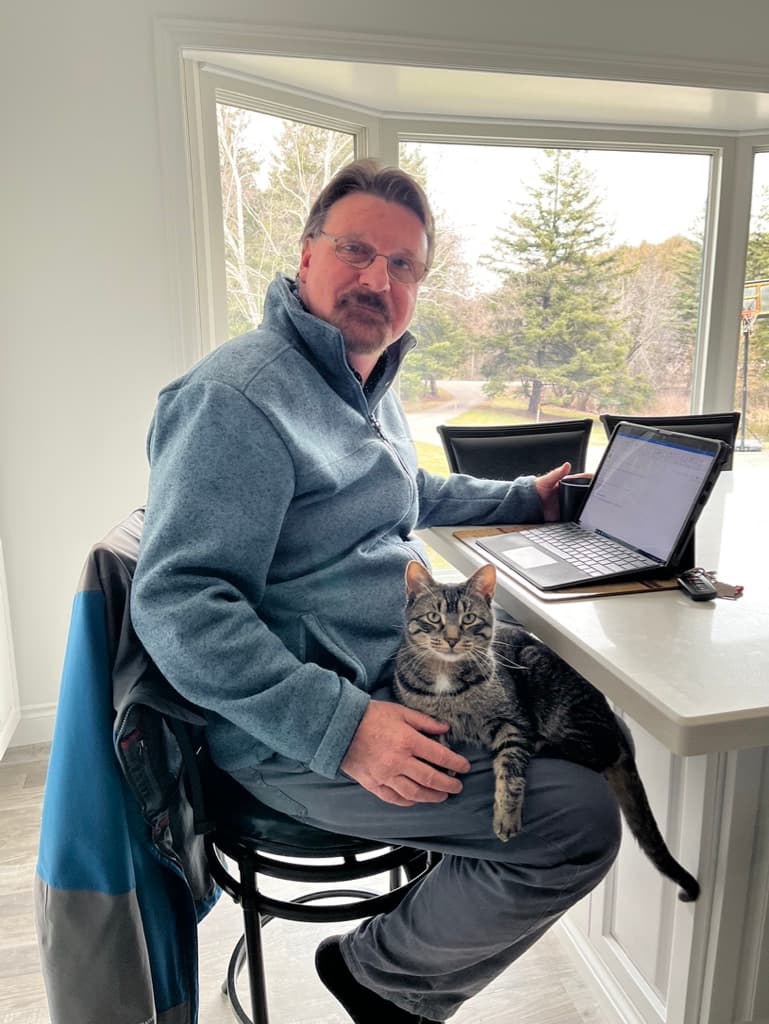 Doug Maskell lavora al computer portatile con Jasper il gatto